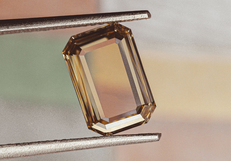 Amber rectangular gemstone held between jeweller's tweezers