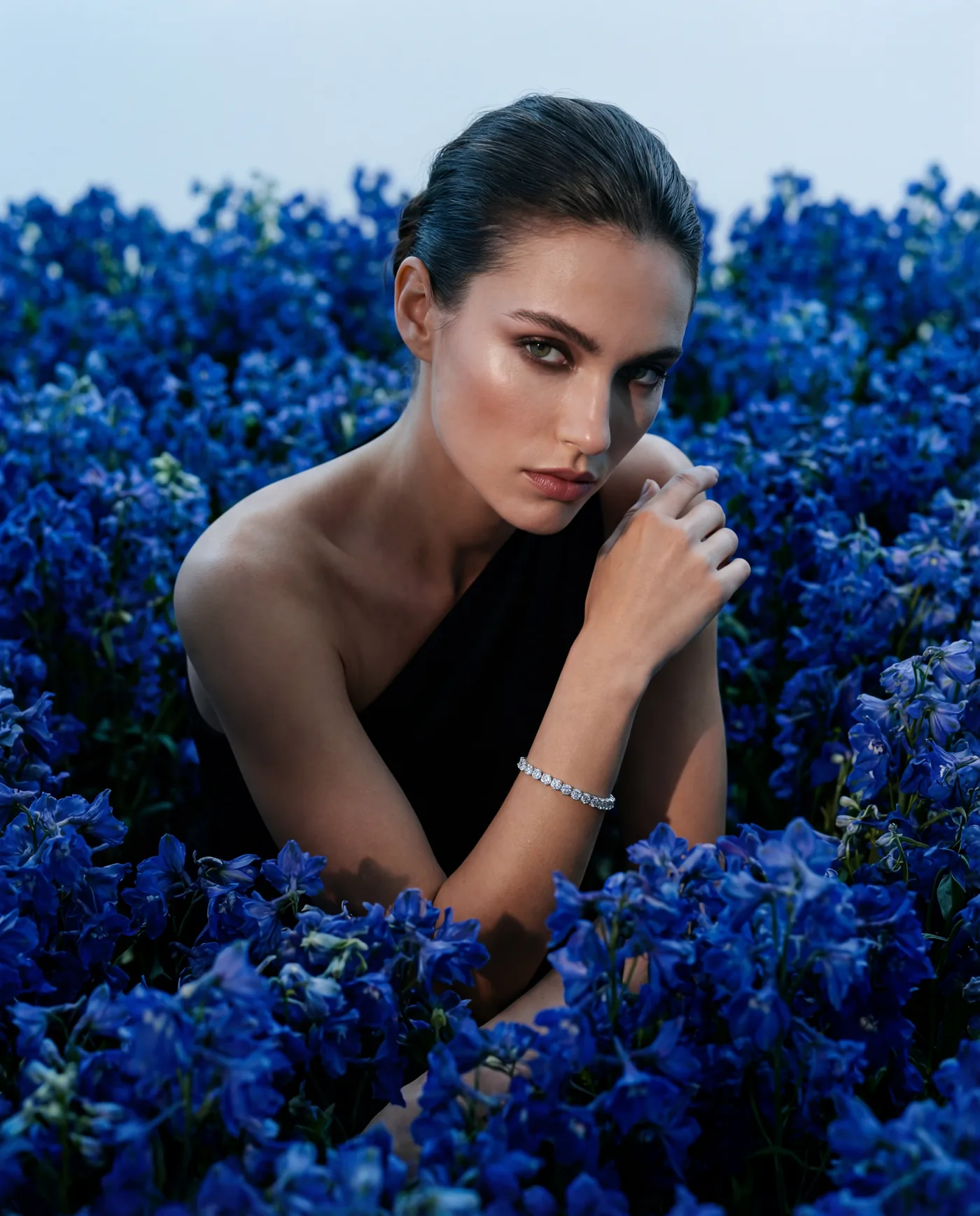 Model wearing a diamond bracelet in a field of blue delphiniums